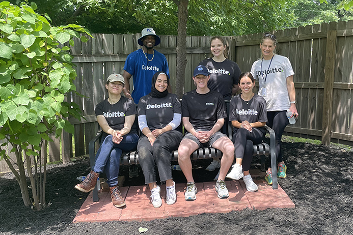 Group of volunteers outside on and by a bench