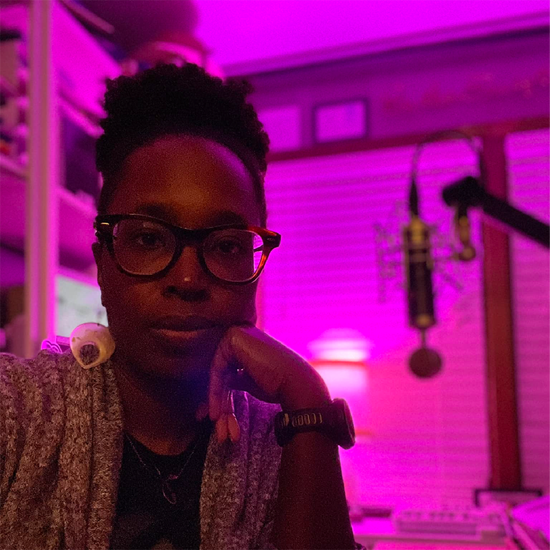 Person facing camera with purple light on in the background