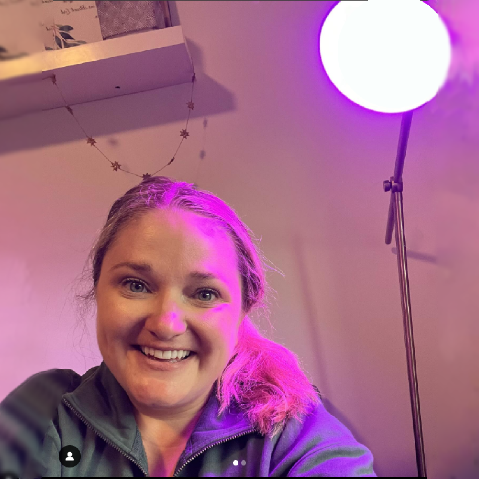 Person smiling at camera with purple light shining in the background