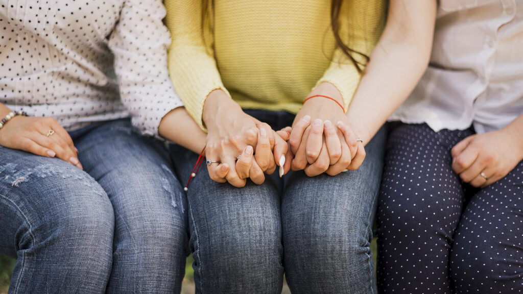 Two young sisters hold hands with their aunt, who has taken care of them since losing their mother to domestic violence.