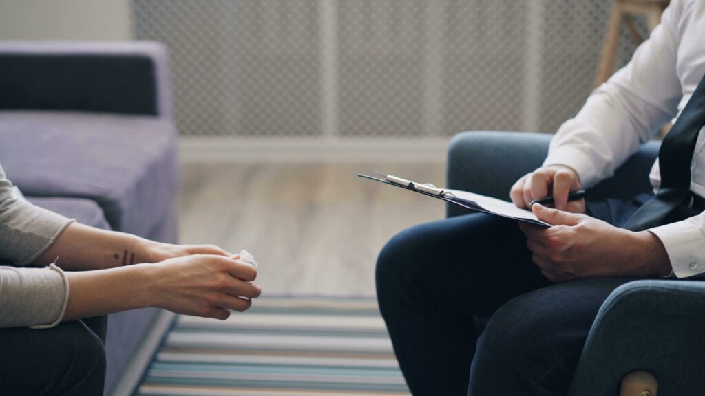 Therapist sits opposite a client on furniture.